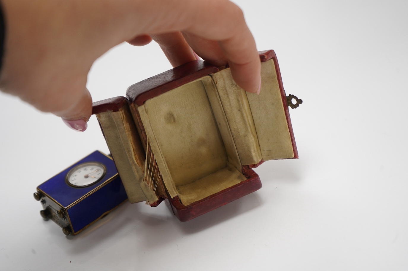 An early 20th century enamelled metal miniature carriage timepiece, cased, 6cm tall. Condition - case poor to fair, clock fair to good